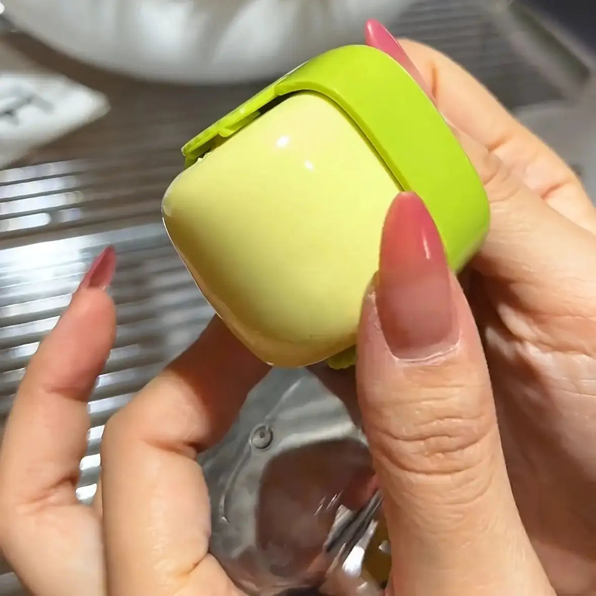 Green and yellow portable lint roller with a compact design, being rinsed under water for reuse, ideal for pet hair removal on clothes
